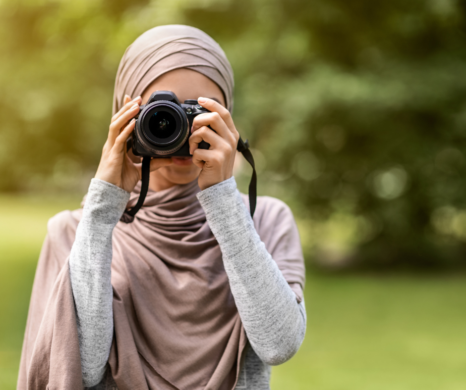 a person outside, holding a camera up to their face