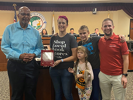 Photo of Emily Autnerieth, owner of A Seat at the Table Bookstore accepting the Above and Beyond Award from a Disability Advisory Committee member